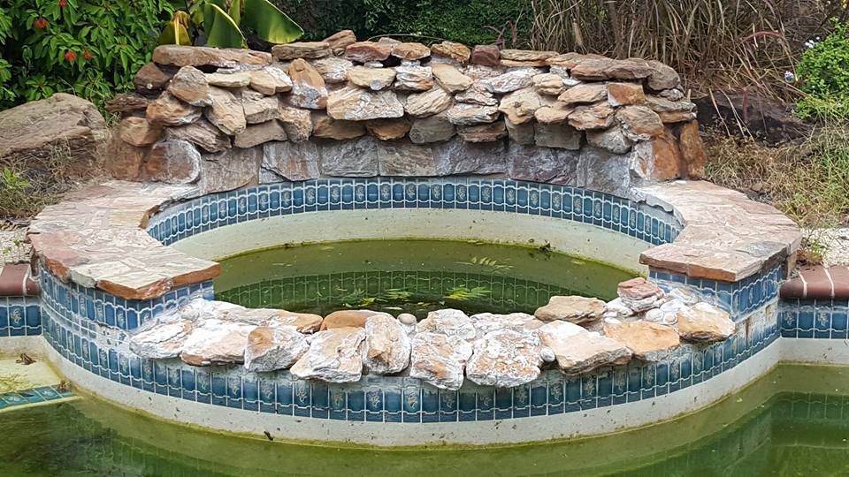 A swimming pool with a stone ledge in the middle of it