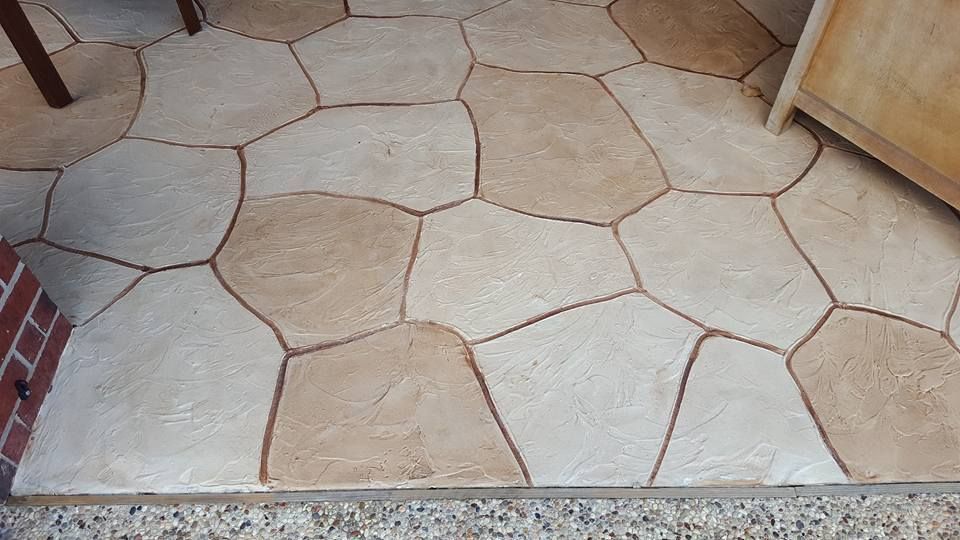 A brown and white tile floor with a brick wall in the background