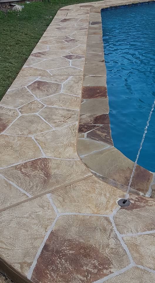 A swimming pool with a stone walkway surrounding it.