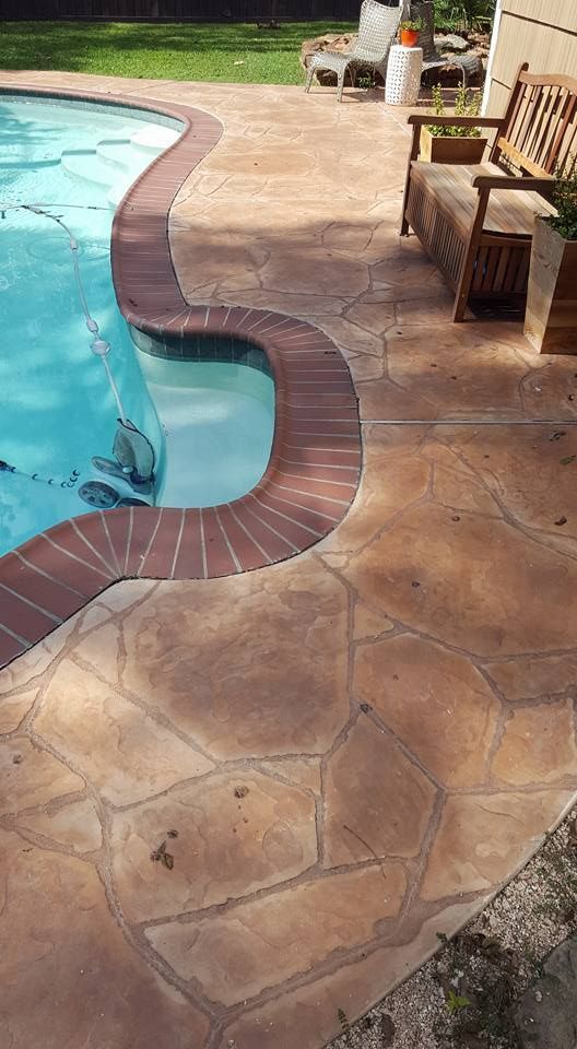 A patio with a bench and chairs next to a swimming pool.