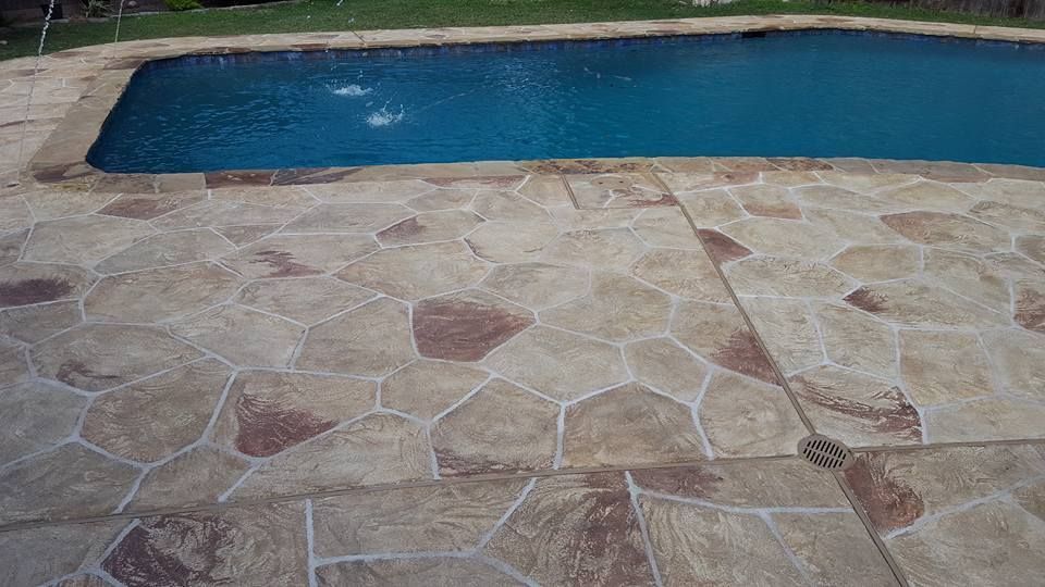 A swimming pool with a stone patio in front of it.