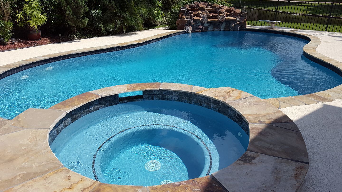 A large swimming pool with a hot tub in the middle of it.