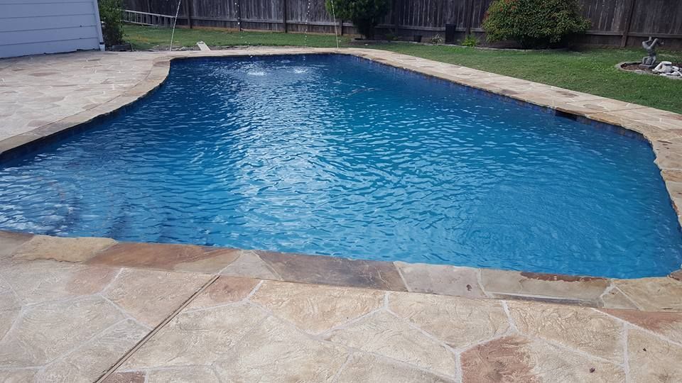 A large swimming pool filled with blue water in a backyard.