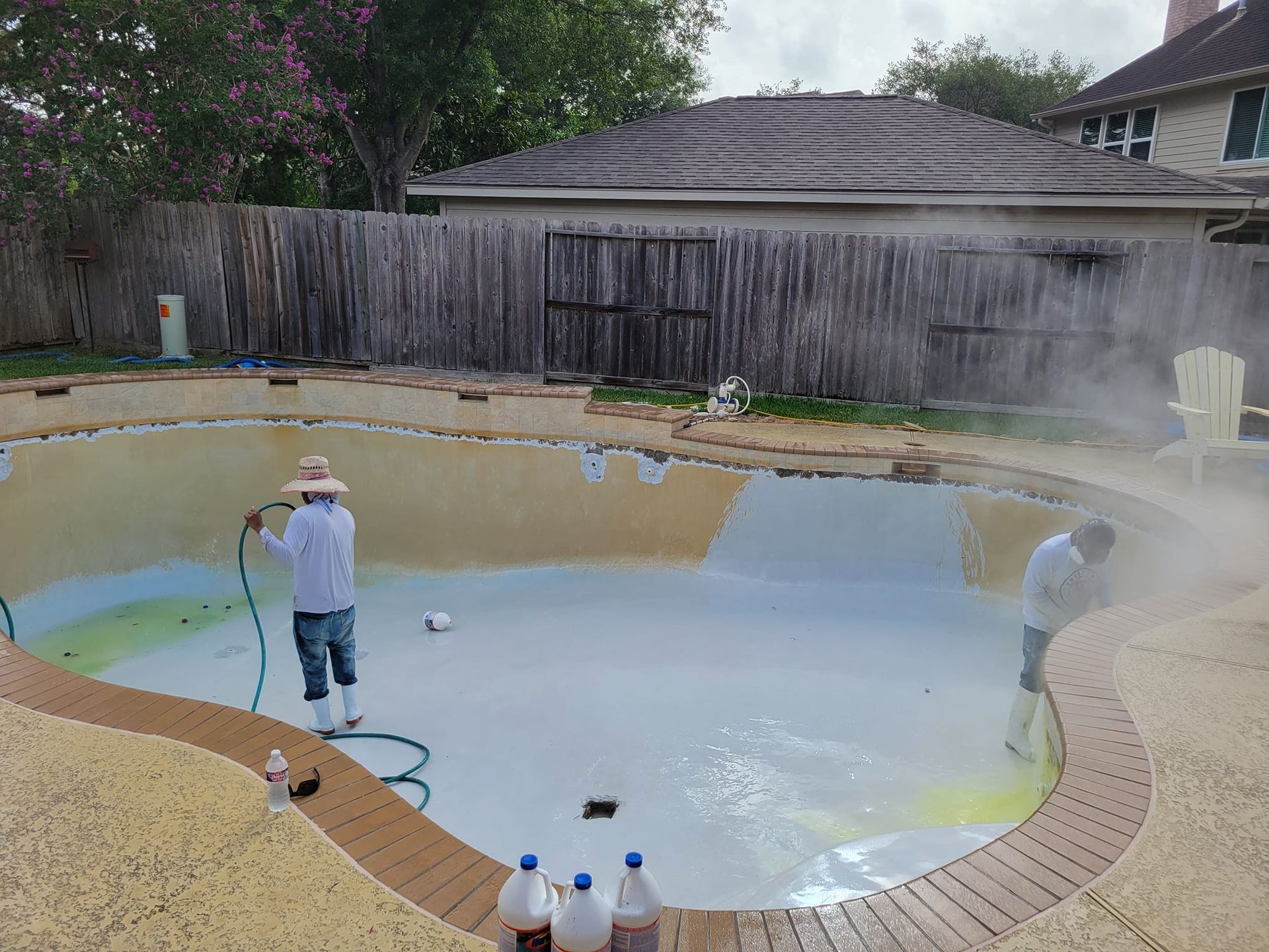 A man is cleaning a swimming pool with a hose.