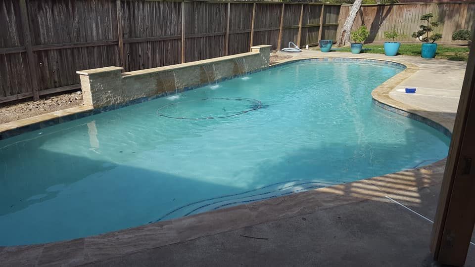 A large swimming pool with a wooden fence in the background.