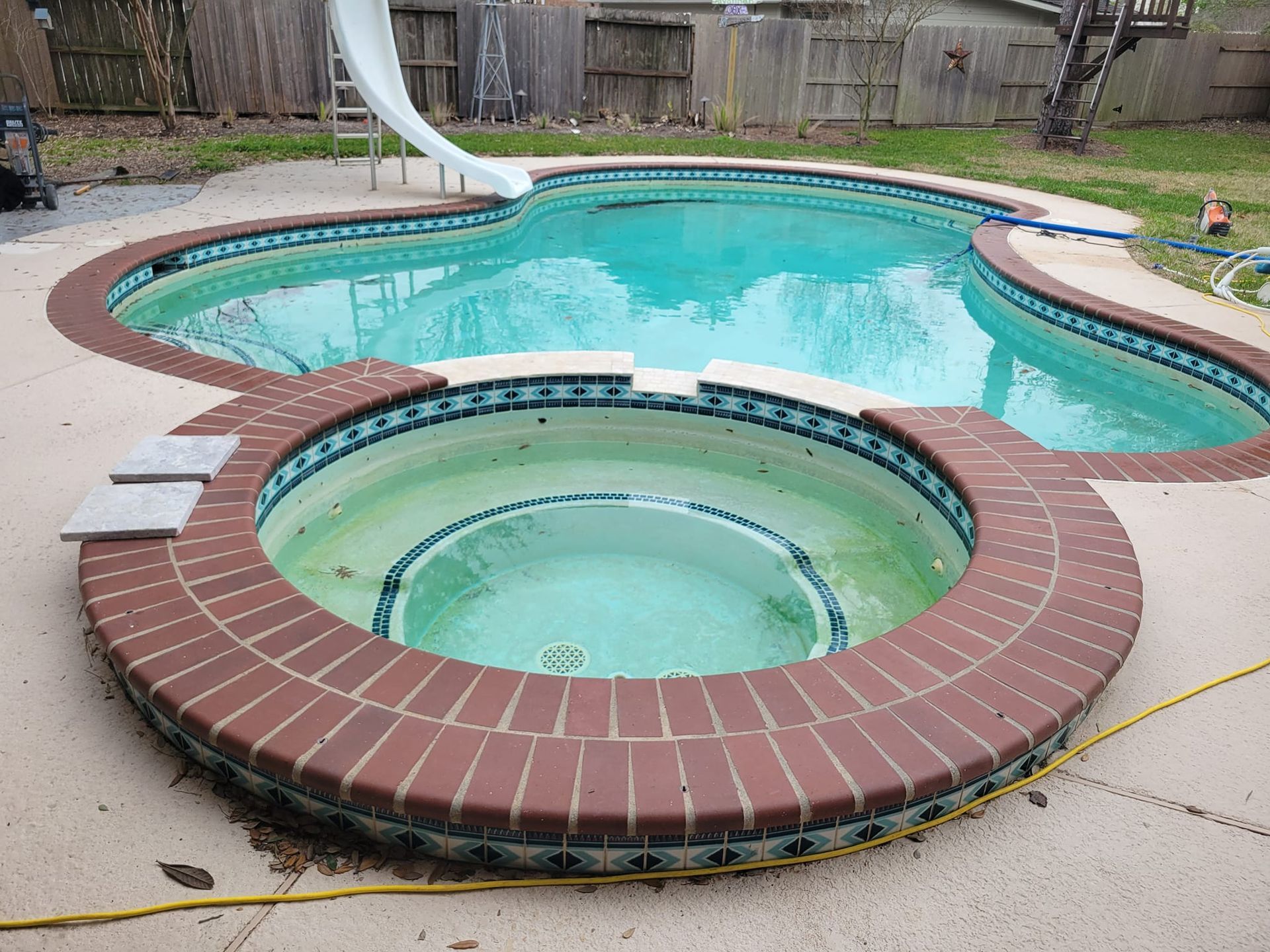 A large swimming pool with a slide and a hot tub