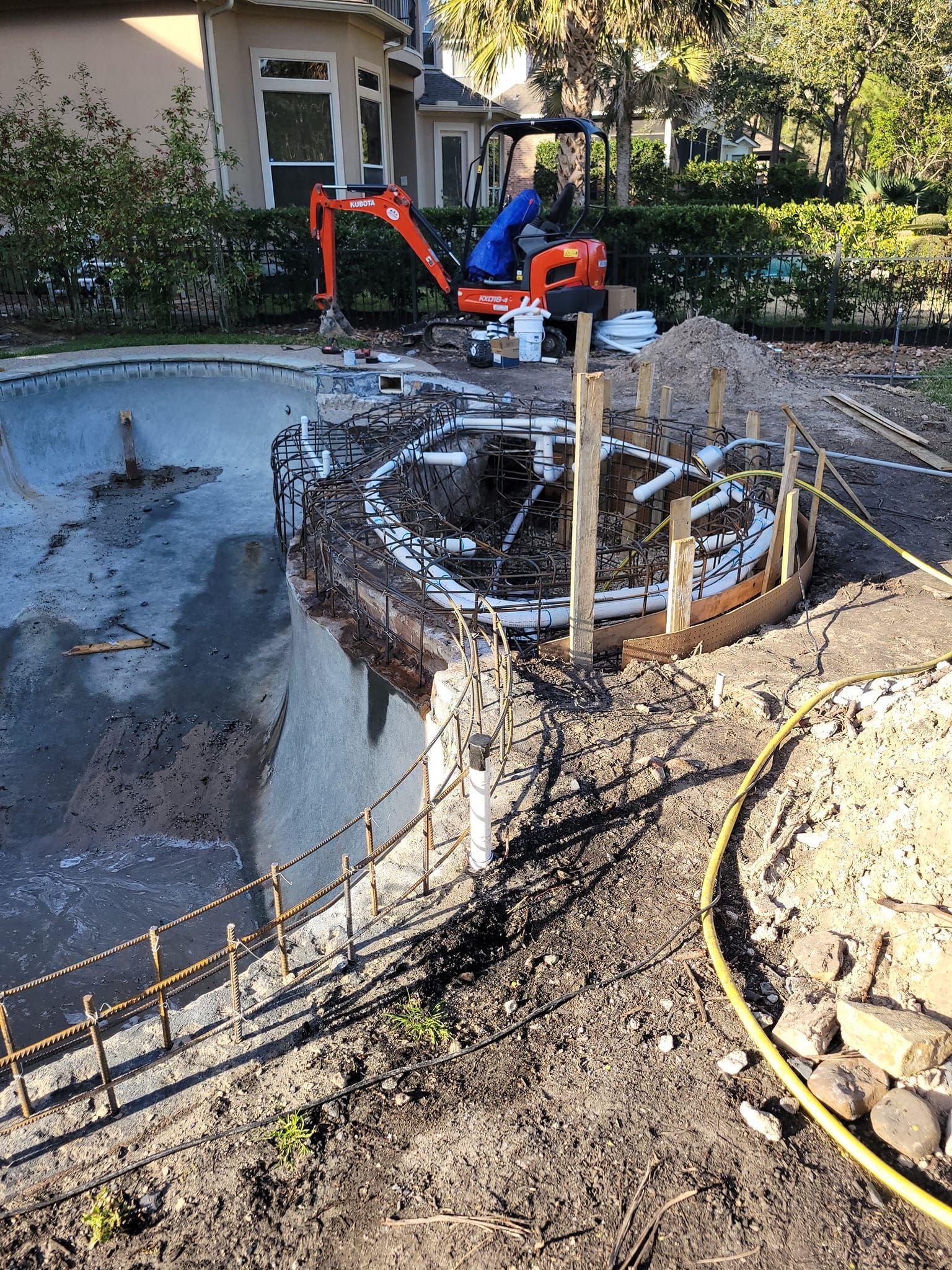 A swimming pool is being built in the backyard of a house.
