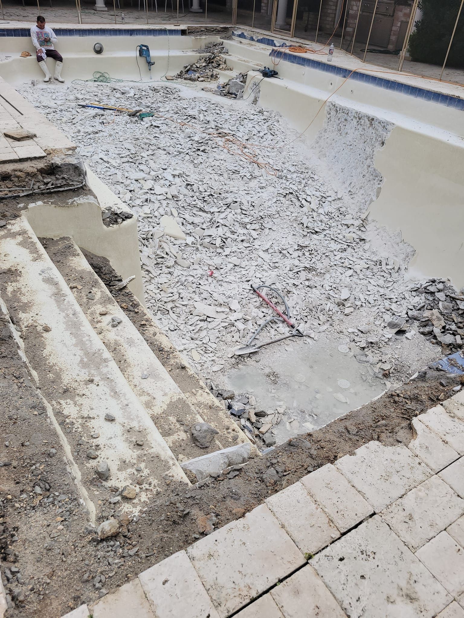 A man is standing next to a swimming pool that is being remodeled.
