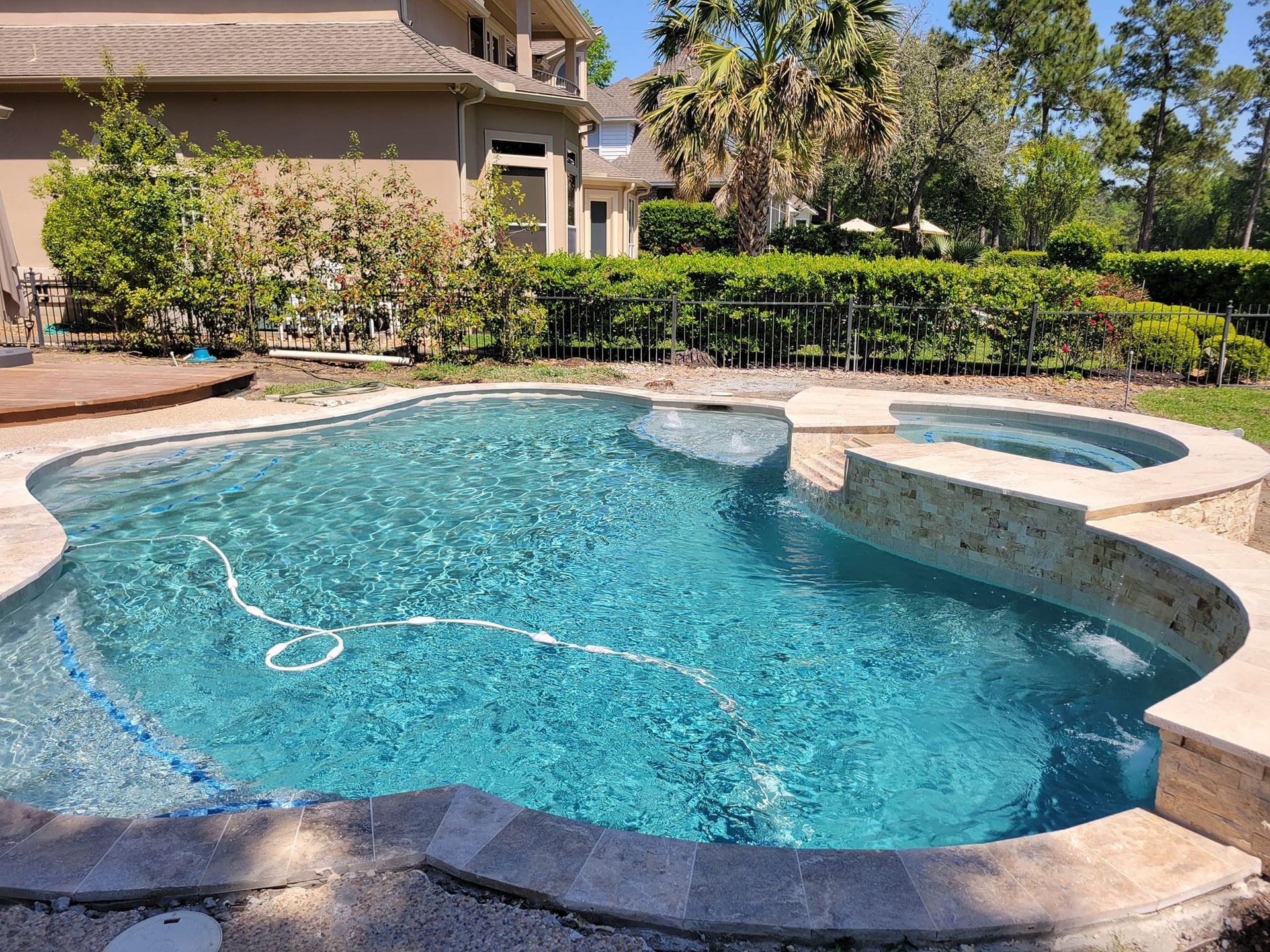 A large swimming pool with a hot tub in the backyard of a house.