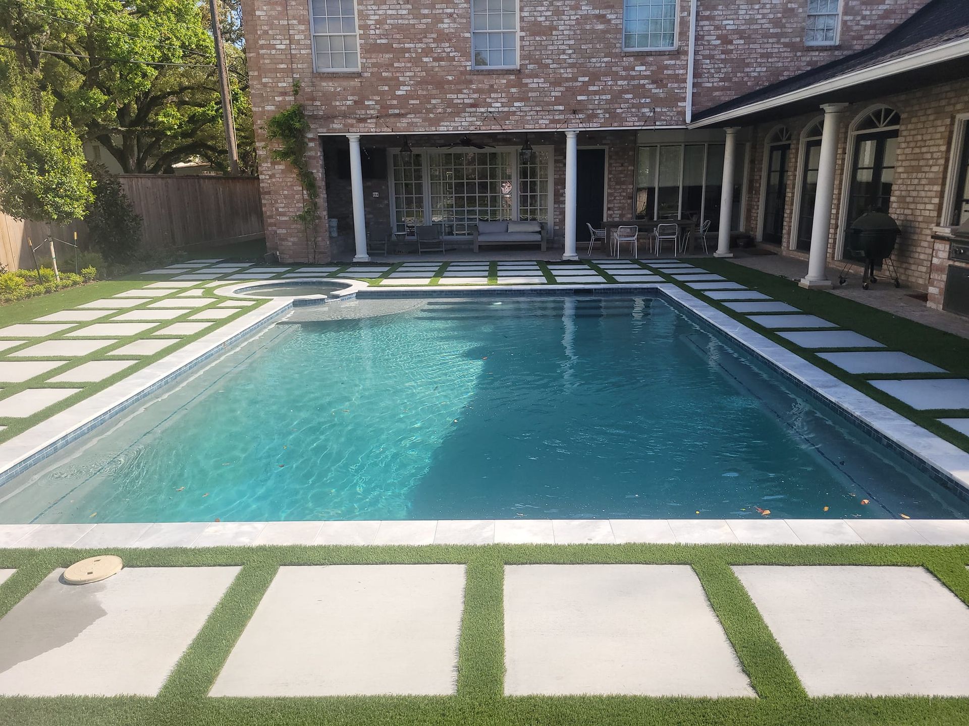 There is a large swimming pool in the backyard of a house.