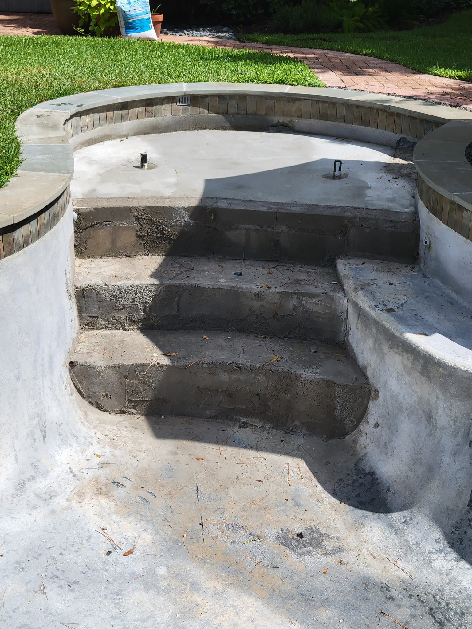 A concrete staircase leading to a swimming pool in a backyard.