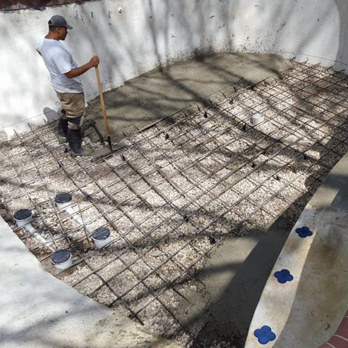 A man with a shovel is working on a concrete floor