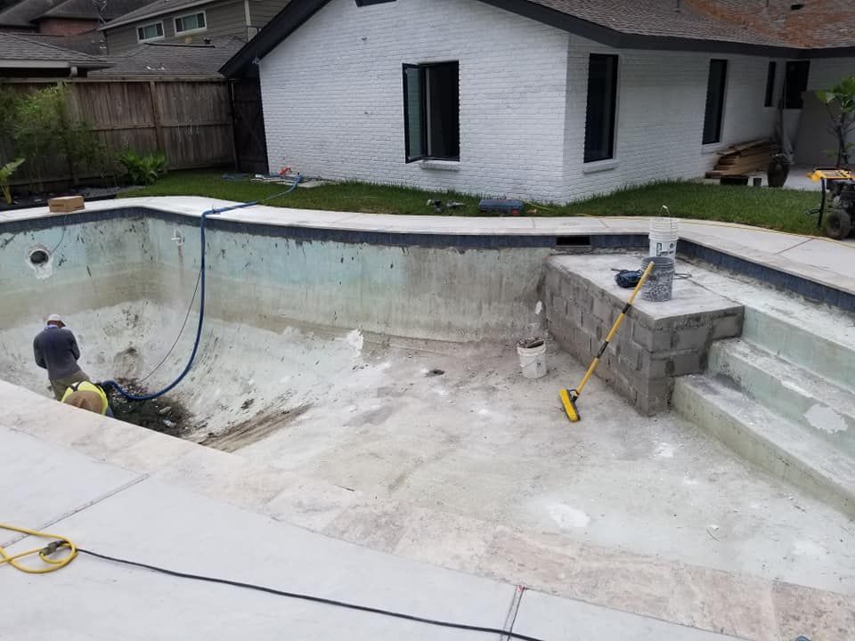 A man is working on a swimming pool in front of a house.