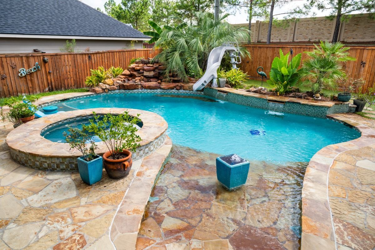 A large swimming pool with a slide in the backyard of a house.