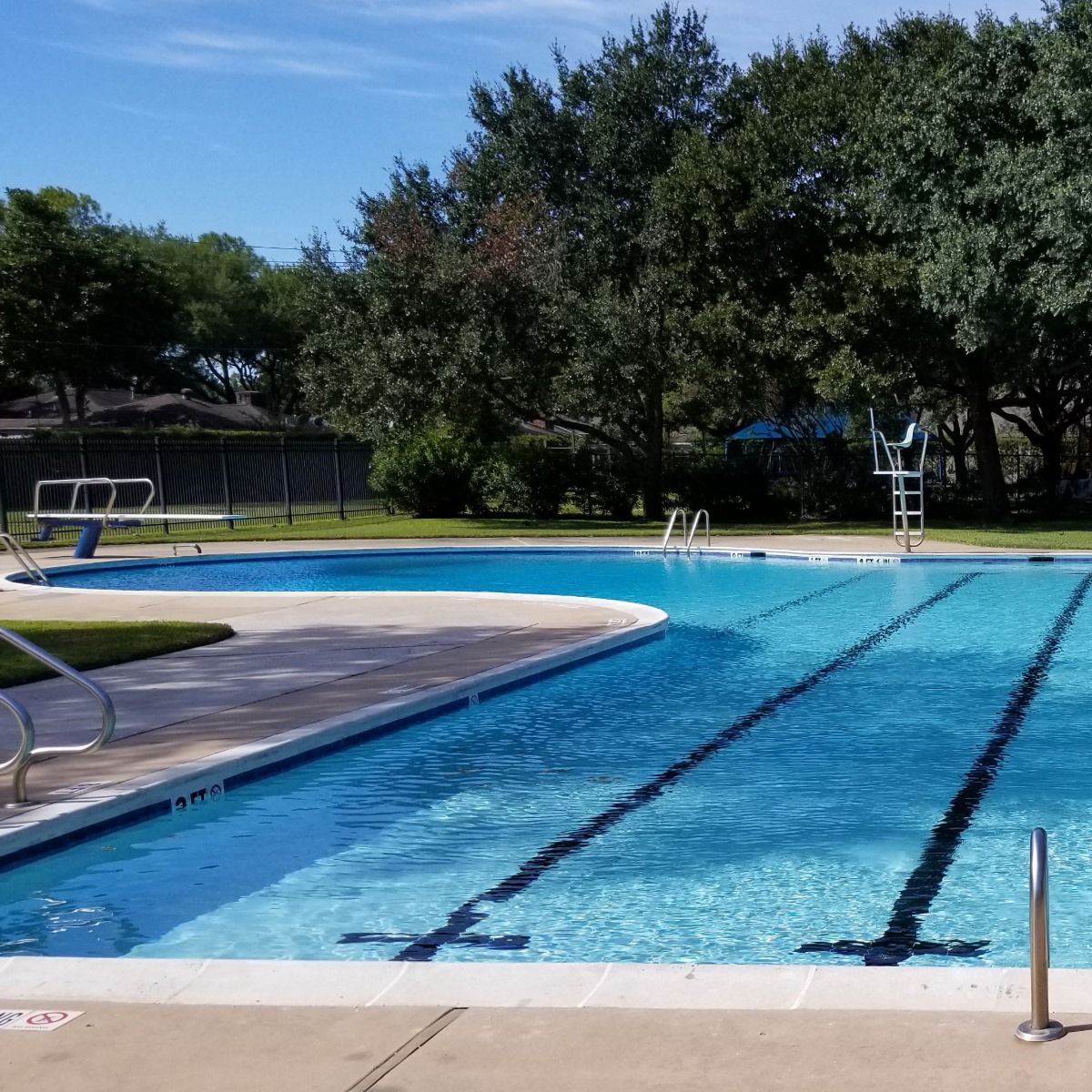 A large swimming pool with a diving board in the background