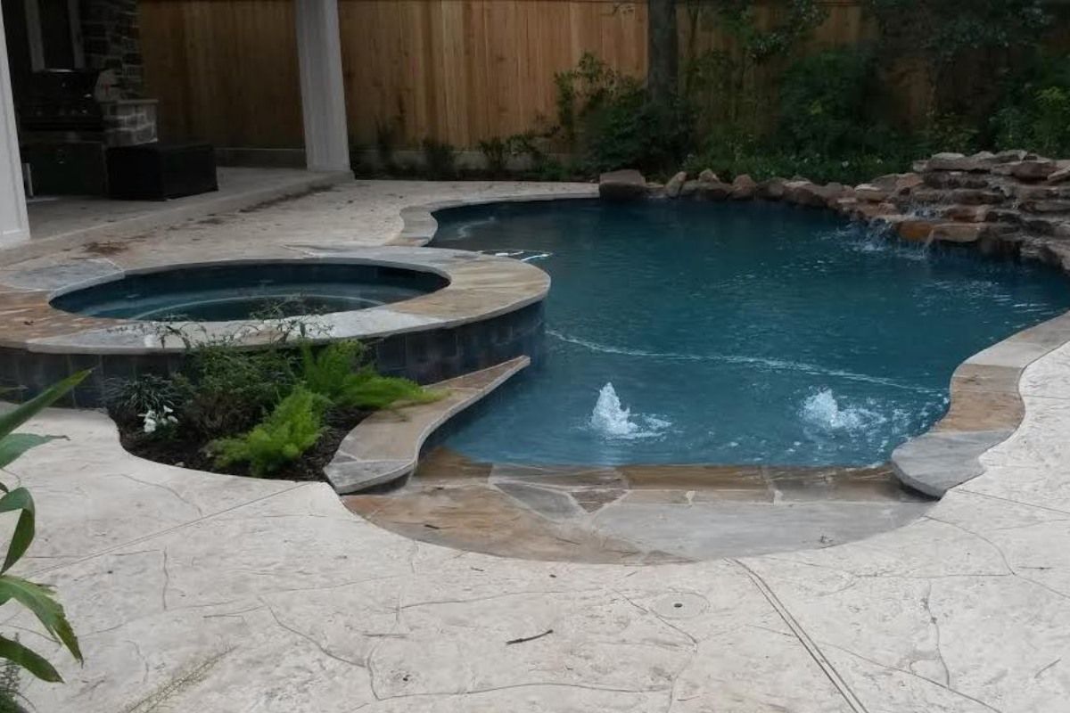A large swimming pool with a hot tub in the backyard.