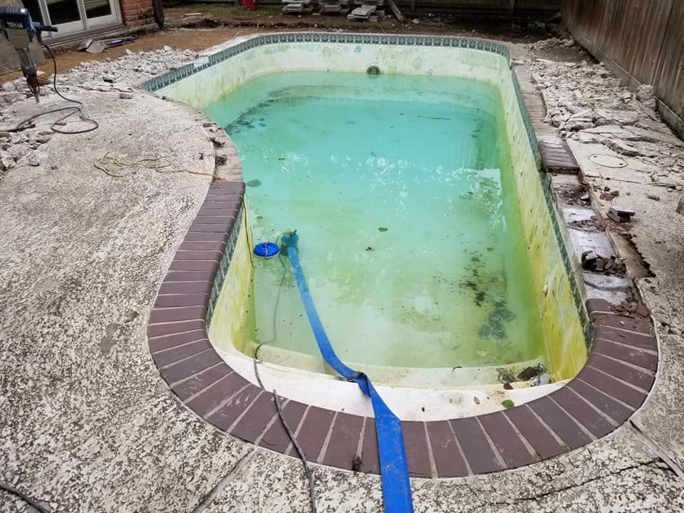 A dirty swimming pool with a blue hose attached to it.