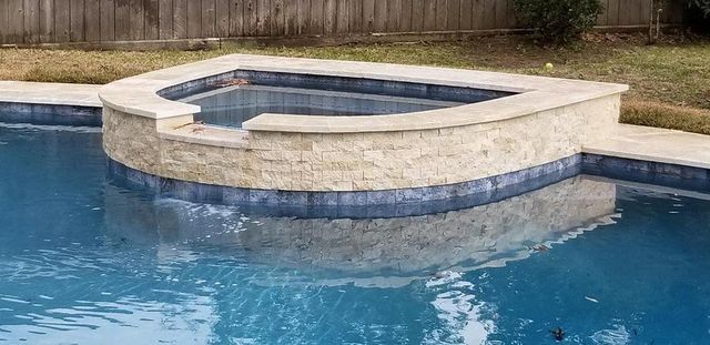 A large swimming pool with a hot tub in the middle of it.