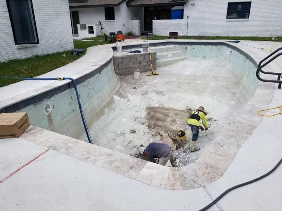 Two men are working on a swimming pool in a backyard.