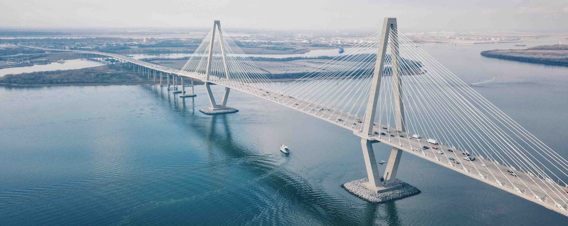 An aerial view of the Arthur Ravenel Jr. Bridge, a cable-stayed bridge spanning a body of water in Charleston, South Carolina.