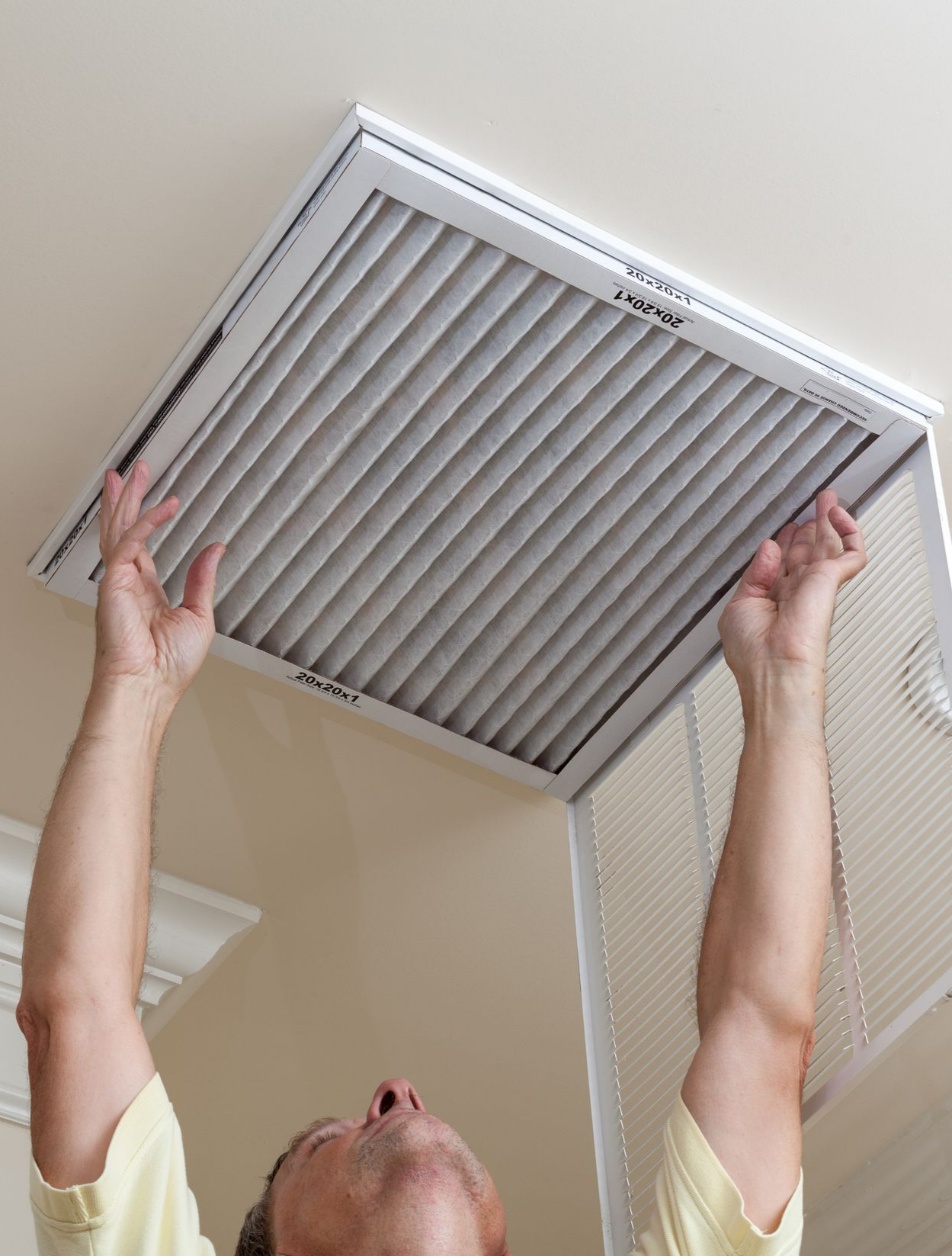 Man opening ceiling air conditioning filter for home duct air care.