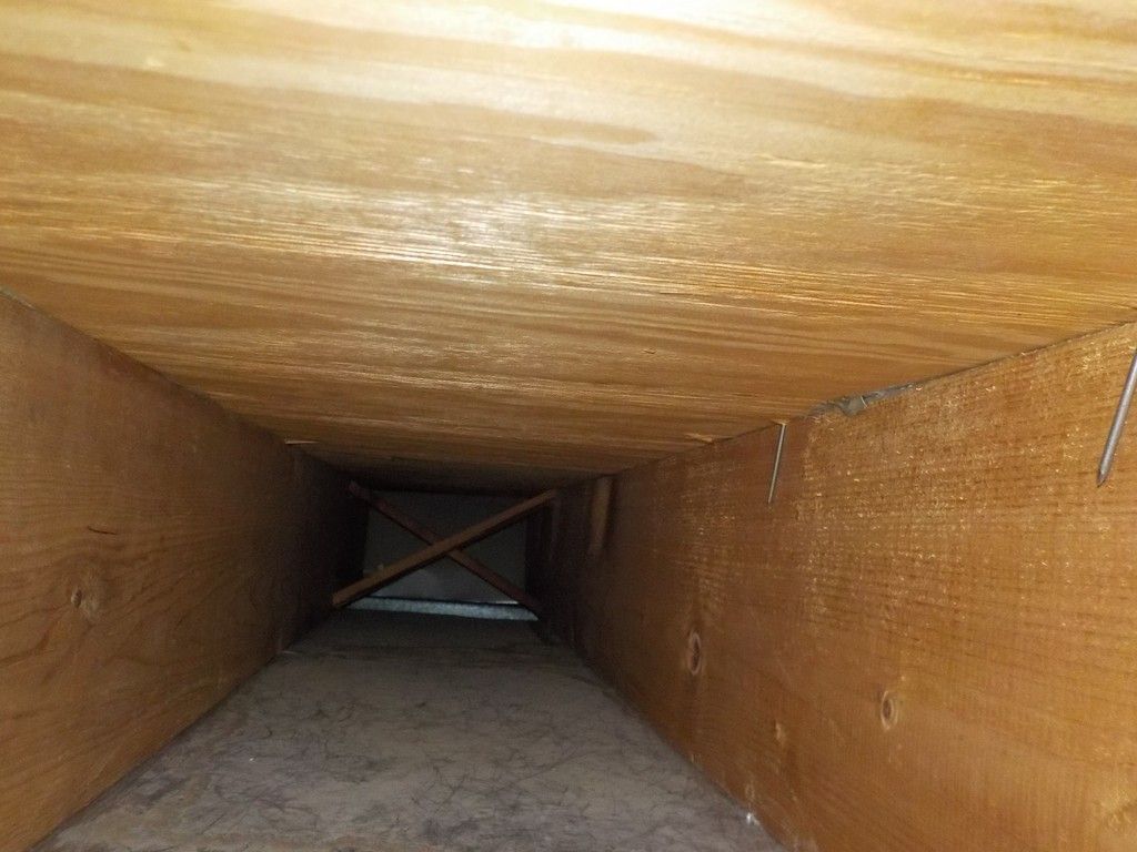 The inside of a wooden tunnel with a wooden ceiling and a wooden floor.