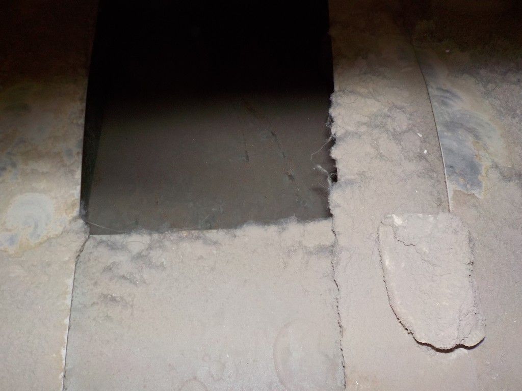 A dirty concrete floor with a hole in the middle of it.