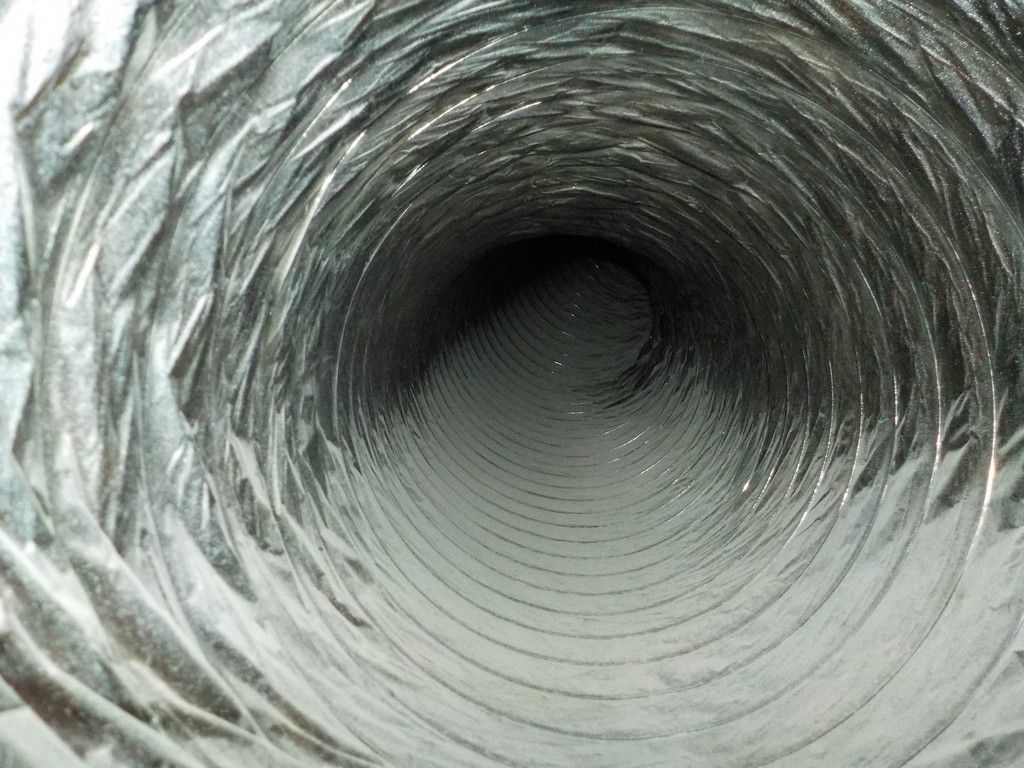 A close up of a metal duct with a hole in the middle.