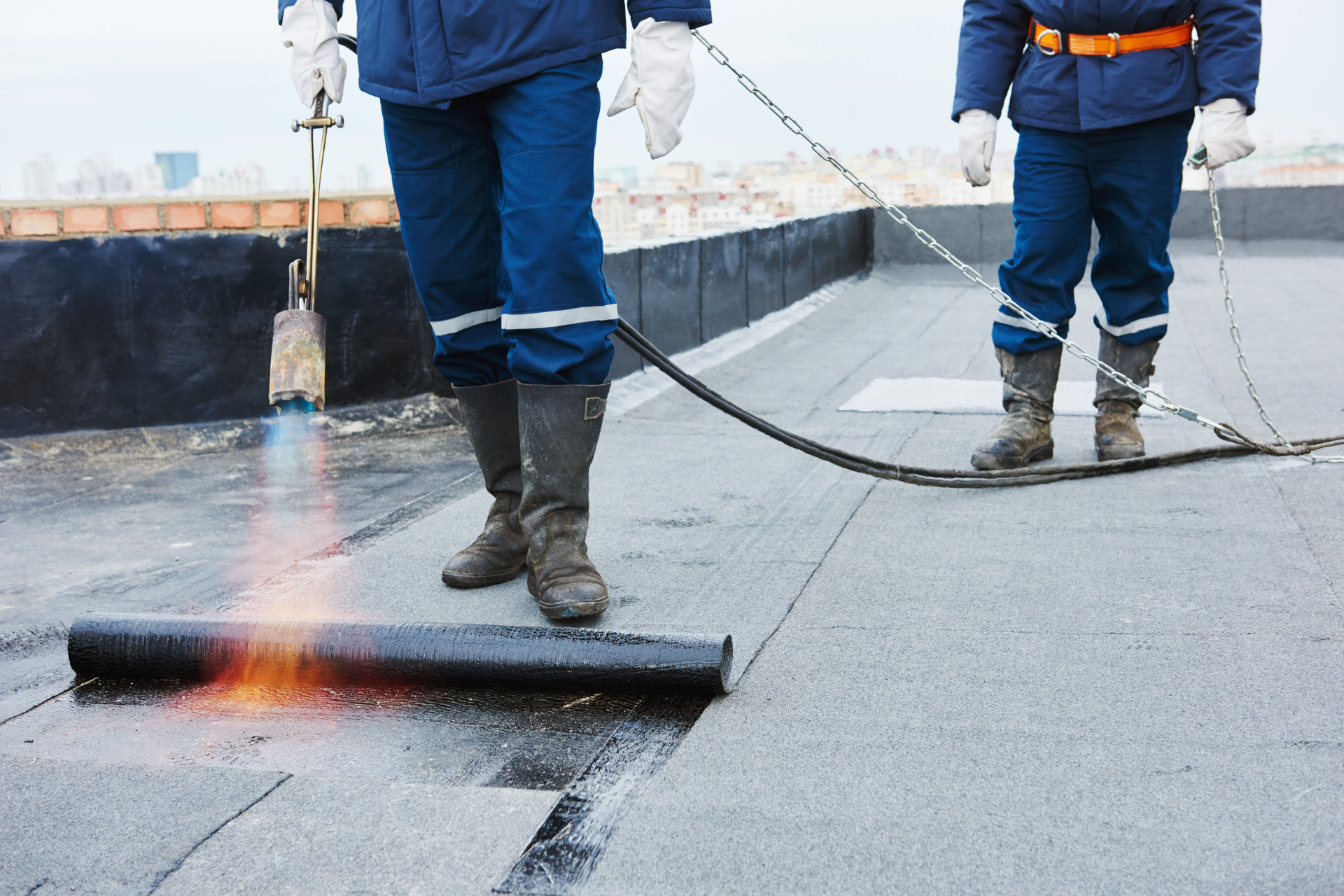 Two ACE workers installing roofing with a blow torch