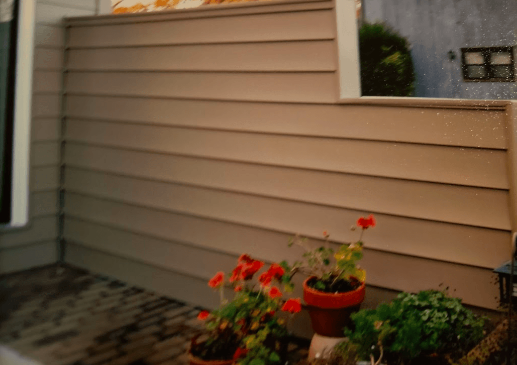 A patio with flowers and potted plants in front of a house.