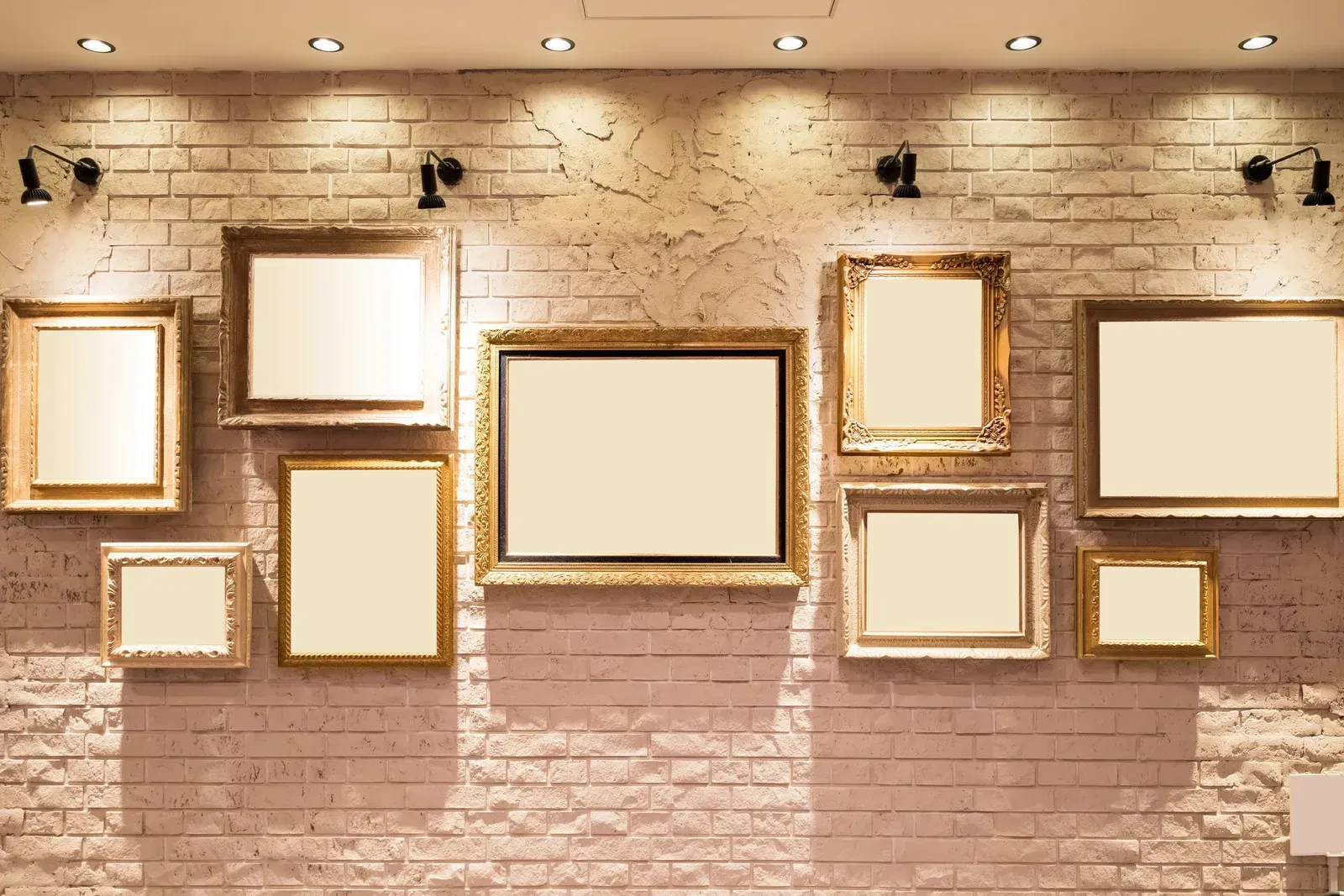 A brick wall with a bunch of picture frames hanging on it.