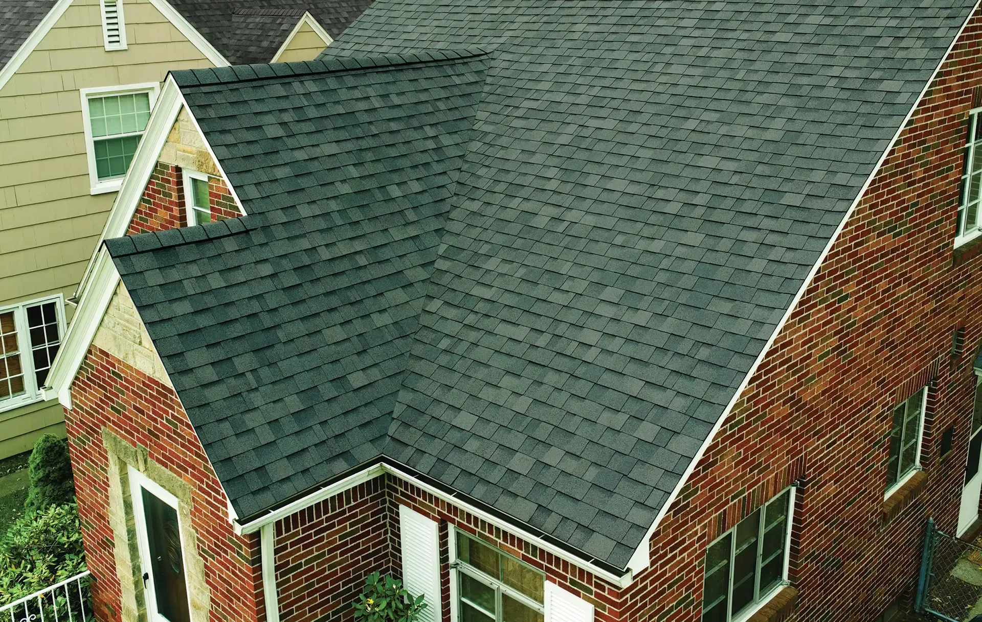 An aerial view of a brick house with a black roof