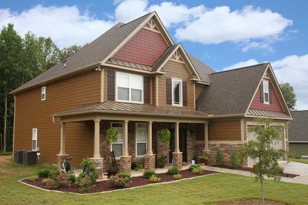 A large house with a large porch and a brown roof