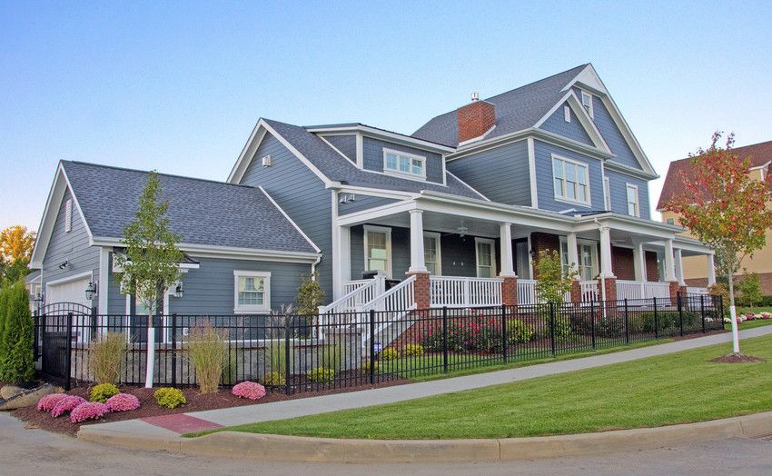 A large house with a large porch and a fence around it.