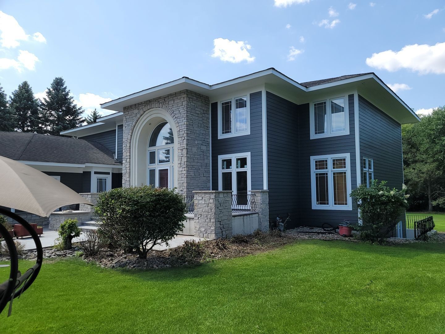 A large house with a lot of windows is sitting on top of a lush green lawn.