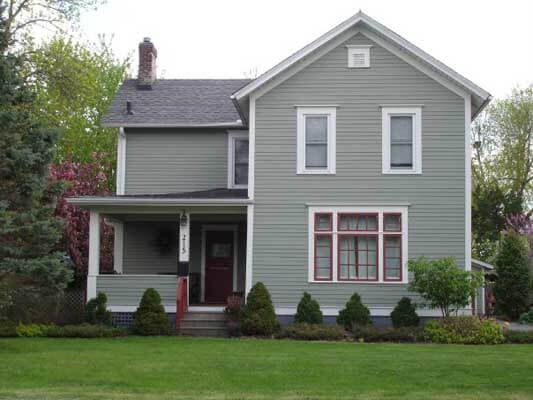 A grey house with a red door and white trim