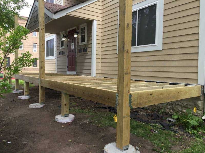 A wooden deck is being built in front of a house.