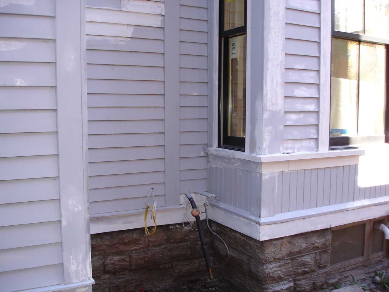 A white house with a window and a hose on the side