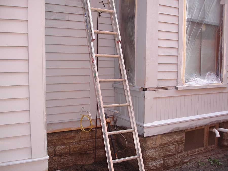 A ladder is leaning against the side of a house.