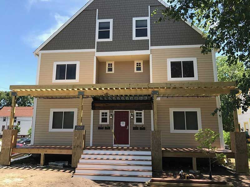 A large house with a wooden deck and stairs in front of it.