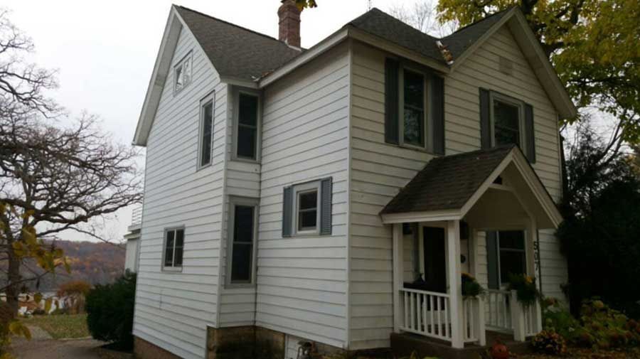 A white house with black shutters and a porch