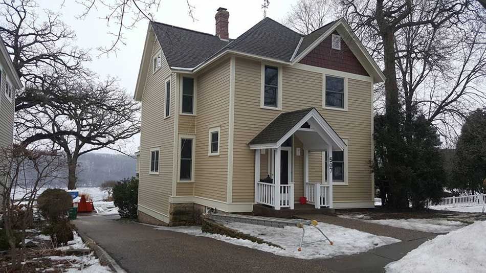 A house with a porch and a car parked in front of it