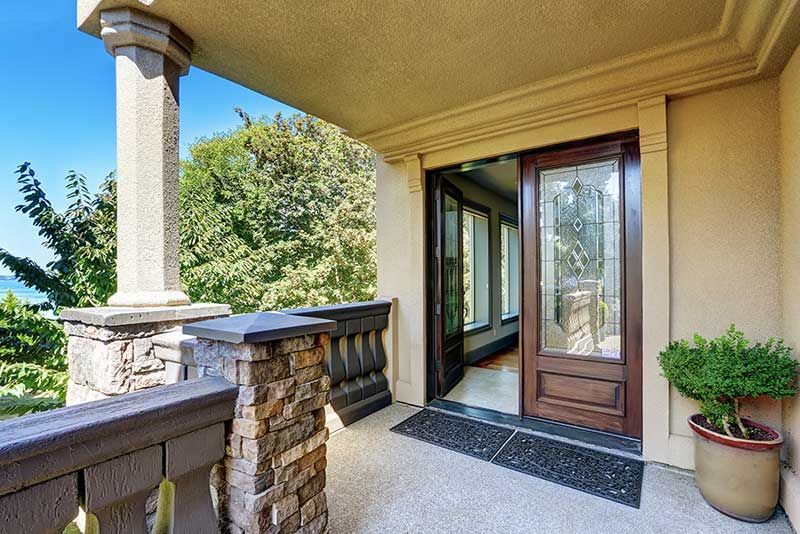 A large porch with a wooden door and a stone railing