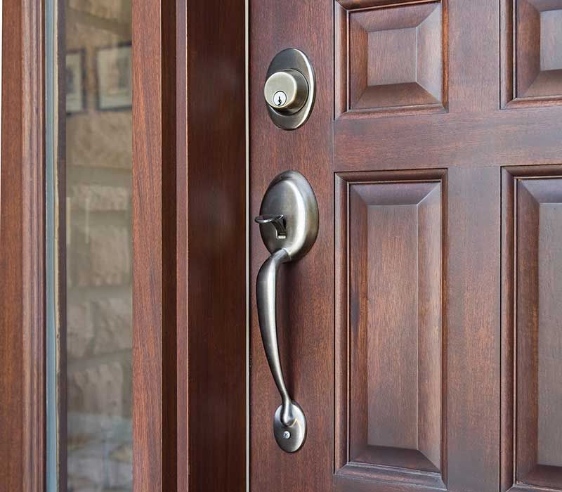 A close up of a door handle on a wooden door.