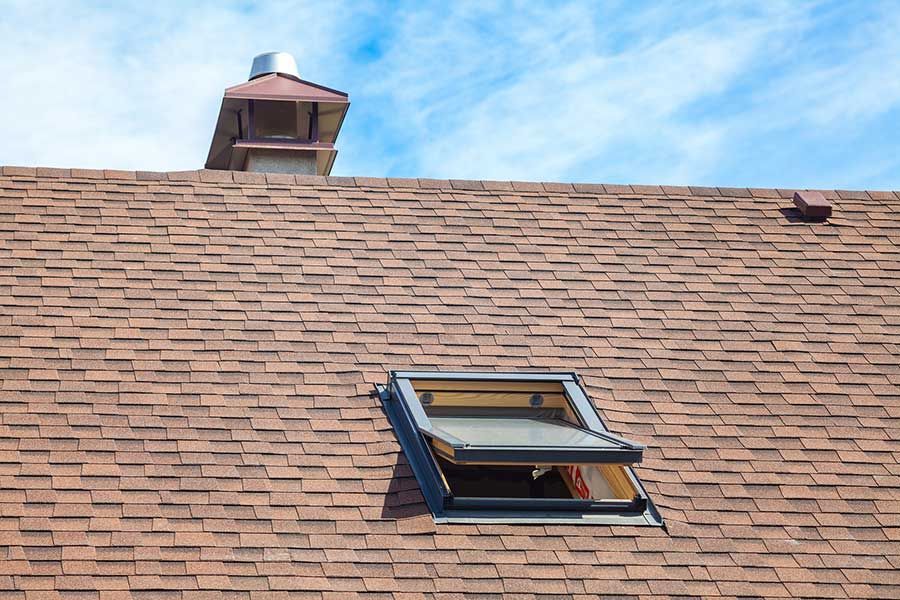 A roof with a skylight and a chimney on it.