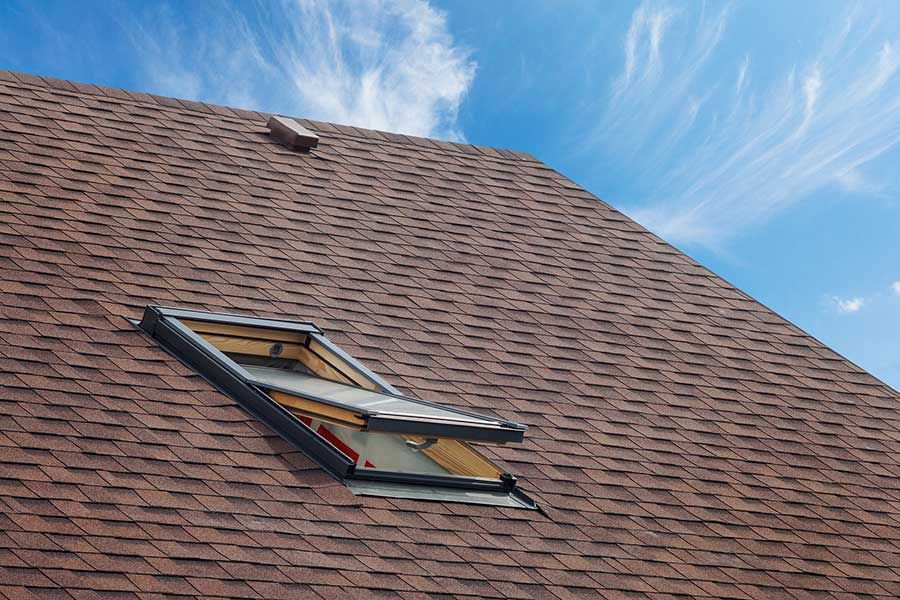 A skylight on the roof of a house with a blue sky in the background.