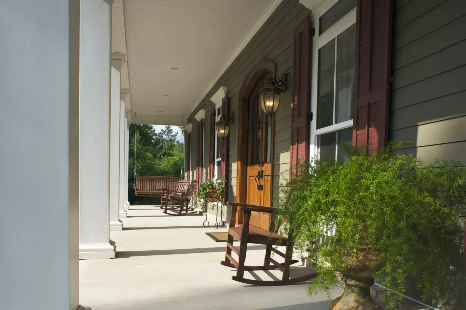 A porch with rocking chairs and a potted plant
