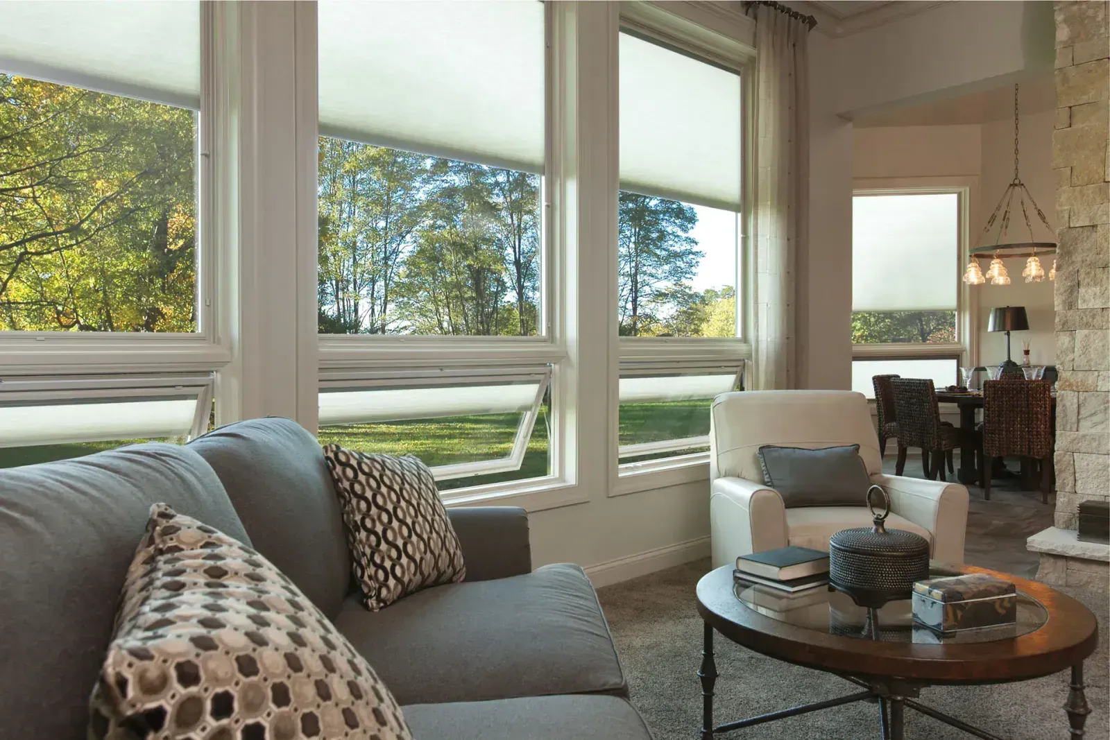 A living room with a couch , chair , coffee table and lots of windows.