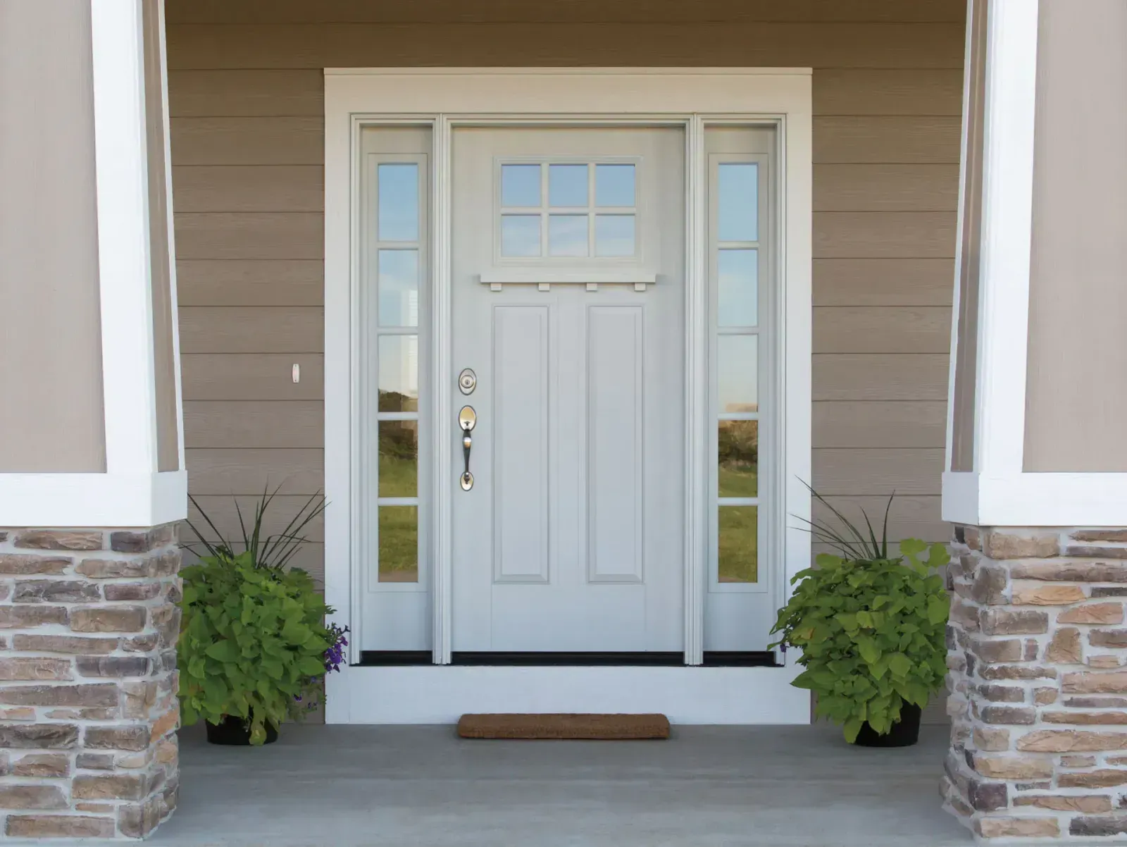 The front door of a house with a porch and plants in front of it.