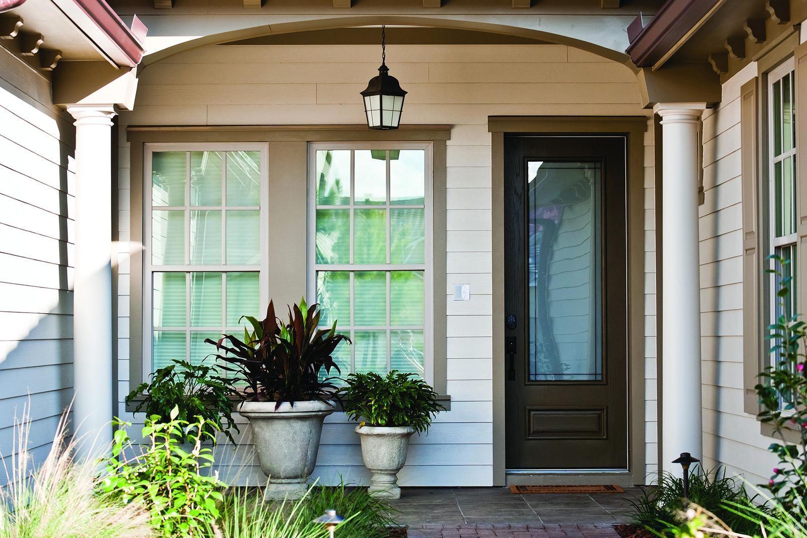 A front porch of a house with potted plants in front of it